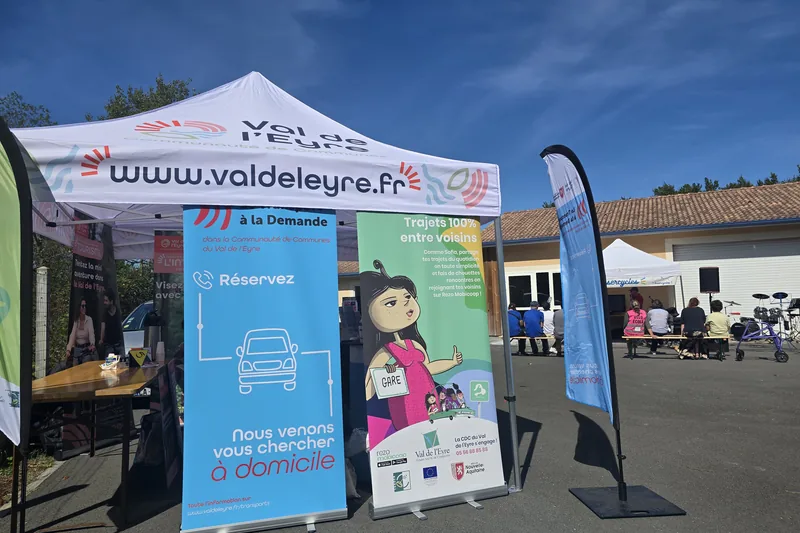 Stand du Val de l’Eyre au forum Mobil’Eyre : kakémonos sur le transport à la demande et sur Rezo Pouce, sous un ciel bleu.